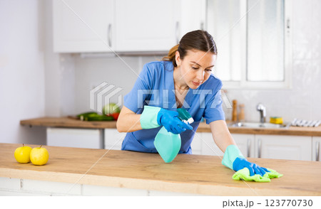 Young woman professional cleaner cleaning desk with detergents in kitchen 123770730