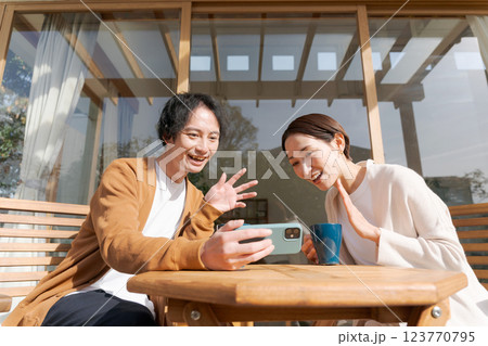 テラスでスマホを操作する夫婦 テラスでスマホを操作する夫婦 123770795