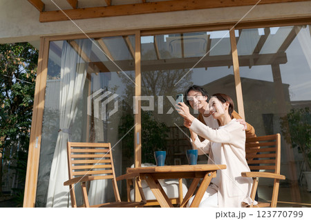 テラスでスマホを操作する夫婦 123770799