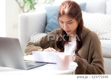 Young asian woman calculates bills finance and cost in living room at home, woman looking expense. Young asian woman calculates bills finance and cost in living room at home, woman looking expense. 123771030