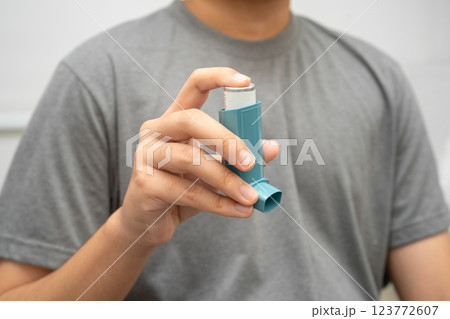 Asthma and chronic obstructive pulmonary disease COPD, Asian young man using metered dose inhaler MDI. 123772607