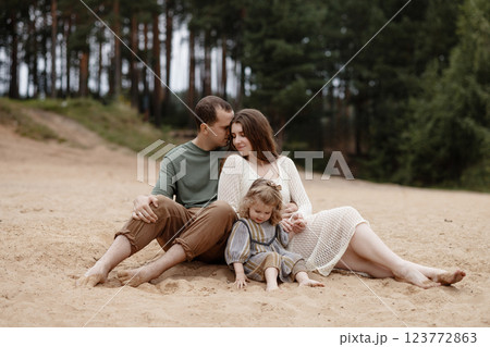A family of three, a man, a woman and a child, are relaxing on the beach. A family of three, a man, a woman and a child, are relaxing on the beach. 123772863