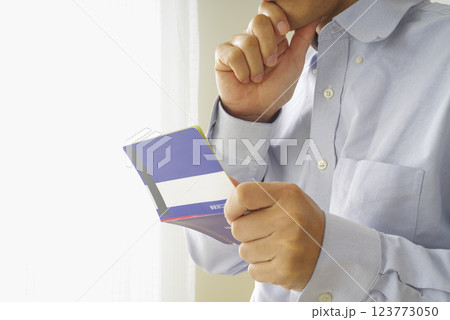 貯金通帳を見つめる中年男性 貯金通帳を見つめる中年男性 123773050