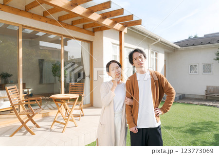 家の庭に立って考える夫婦 123773069