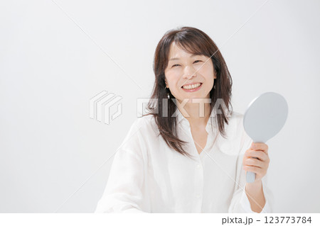 手鏡を持つ笑顔のミドル女性 123773784