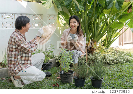 Diverse couple enjoying gardening in a sunny backyard, sharing laughter and plants. 123773936