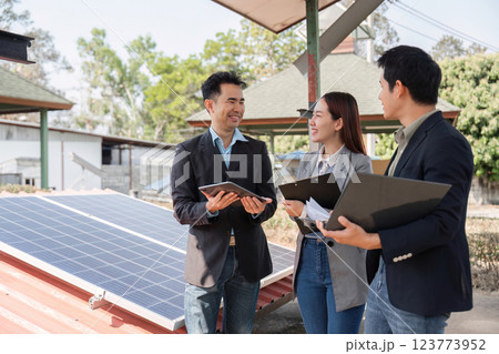 Collaborative energy solutions. Professionals engaged in discussion under solar panels. 123773952