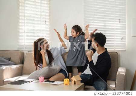 Family expressing joy while learning about savings and finances together Family expressing joy while learning about savings and finances together 123774003