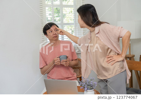 Middle-aged couple having a playful argument indoors with a coffee mug. Middle-aged couple having a playful argument indoors with a coffee mug. 123774067