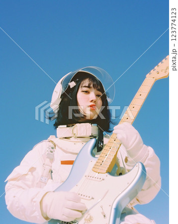 宇宙飛行士の女性とエレキギター - ピンクの背景と未来的ファッション 123774123