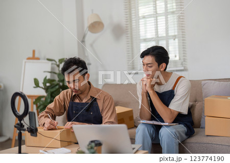 Dynamic duo of online sellers reviewing their business progress in a cozy living room. Dynamic duo of online sellers reviewing their business progress in a cozy living room. 123774190