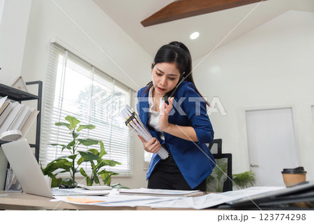Accountant on phone managing tax documents in a modern office setting 123774298