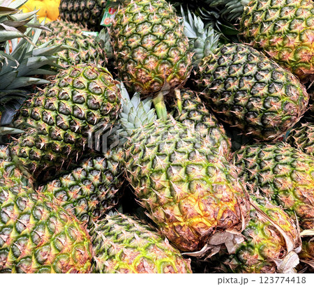 Fresh Pineapples in a Vibrant Market Display of Tropical Fruits, Colorful display of fresh, ripe pineapples at a market showcasing a tropical atmosphere 123774418