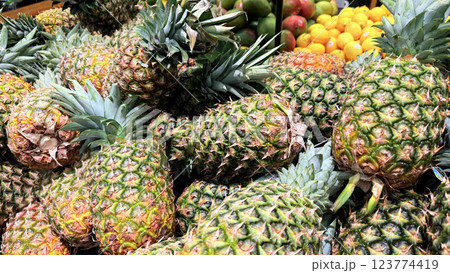 Fresh Pineapples in a Vibrant Market Display of Tropical Fruits, Colorful display of fresh, ripe pineapples at a market showcasing a tropical atmosphere 123774419