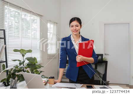 Businesswoman reviewing financial documents in a modern office setting, showcasing professionalism and organization. Businesswoman reviewing financial documents in a modern office setting, showcasing professionalism and organization. 123774434