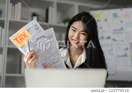 Smiling businesswoman holding tax forms and discussing financial details, emphasizing her role in finance. 123774519