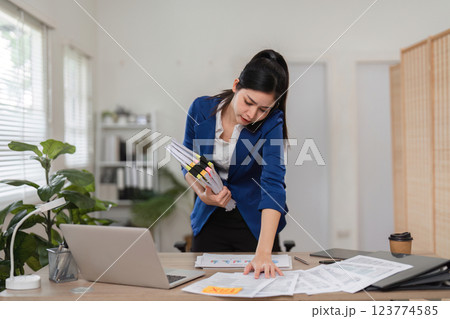 Accountant on the phone while managing tax documents and reports in a busy office. 123774585