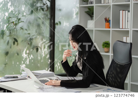 Accountant working on a laptop while engaging in a financial discussion over the phone. Accountant working on a laptop while engaging in a financial discussion over the phone. 123774746