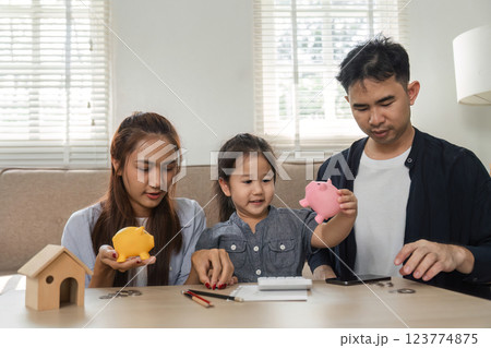 Family engaging in saving activities with piggy banks and a calculator at home Family engaging in saving activities with piggy banks and a calculator at home 123774875