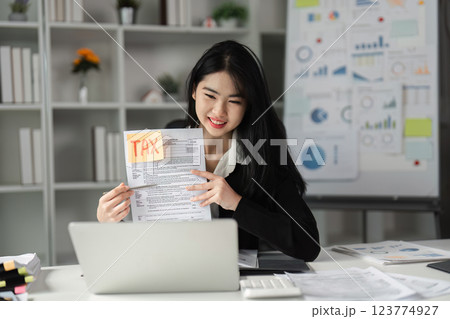 Businesswoman showcasing tax documents in a modern office setting. Businesswoman showcasing tax documents in a modern office setting. 123774927
