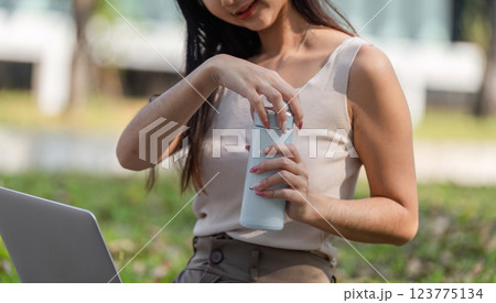 Eco-conscious habits. Woman opening a reusable water bottle while enjoying nature. Eco-conscious habits. Woman opening a reusable water bottle while enjoying nature. 123775134
