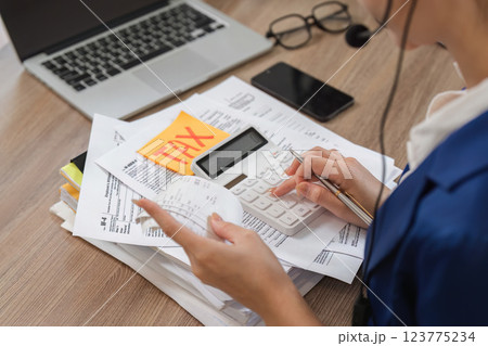Accountant calculating taxes with a calculator and reviewing financial documents. 123775234