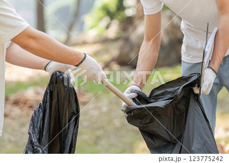 Volunteers collecting trash during a park cleanup, highlighting the importance of community involvement in environmental efforts. 123775242