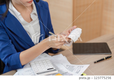 Accountant reviewing receipts and tax documents, using a calculator to ensure accurate financial reporting. 123775256