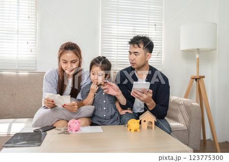 Family reviewing financial documents while teaching their child about budgeting and savings. Family reviewing financial documents while teaching their child about budgeting and savings. 123775300