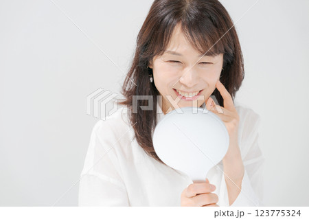 手鏡を持つ笑顔のミドル女性 123775324