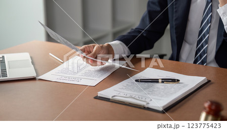 Lawyer examining contract documents with pen and laptop on desk in modern office. 123775423