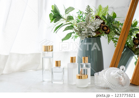 窓辺に並べた金色のキャップのガラス製化粧品ボトル 窓辺に並べた金色のキャップのガラス製化粧品ボトル 123775821