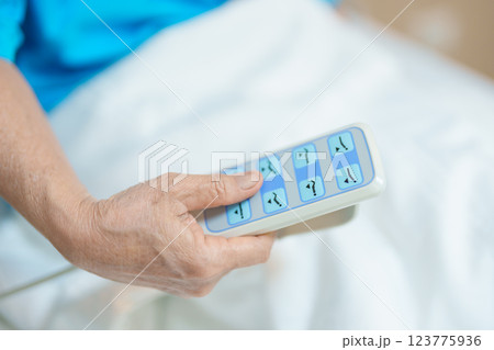Elderly asian Woman patient hand using remote control for adjust level bed in hospital room. Happy Senior illness resting on comfortable electric bed in modern hospital 123775936