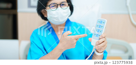 Elderly asian Woman patient hand using remote control for adjust level bed in hospital room. Happy Senior illness resting on comfortable electric bed in modern hospital Elderly asian Woman patient hand using remote control for adjust level bed in hospital room. Happy Senior illness resting on comfortable electric bed in modern hospital 123775938