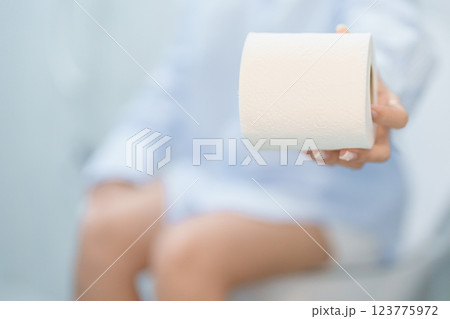 Woman holding toilet paper roll while sitting on toilet bowl. digestion, constipation, Diarrhea from food poisoning, infection, abdominal, stomachache, cystitis, Insurance, Health care and Medical 123775972
