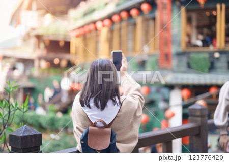 woman traveler traveling in Taiwan, female Tourist taking photo by mobile phone at Jiufen Old Street village with Tea House background. Popular landmarks and attractions near Taipei City woman traveler traveling in Taiwan, female Tourist taking photo by mobile phone at Jiufen Old Street village with Tea House background. Popular landmarks and attractions near Taipei City 123776420