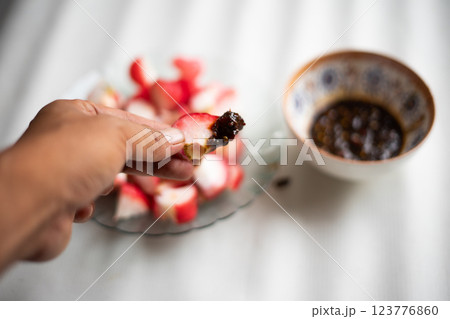 A hand holds a slice of fresh water apple dipped in spicy sambal, 123776860