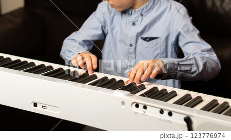 Child playing the keyboard with focused hands and fingers. Child playing the keyboard with focused hands and fingers. 123776974