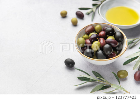 Bowl of assorted olives with olive oil and olive branches on marble background 123777423