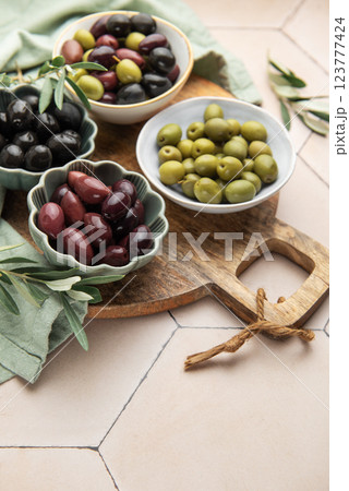 Green, black and kalamata olives in bowls on wooden board 123777424