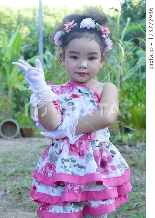 Little girl in flower dress on a swing in the garden Little girl in flower dress on a swing in the garden 123777936