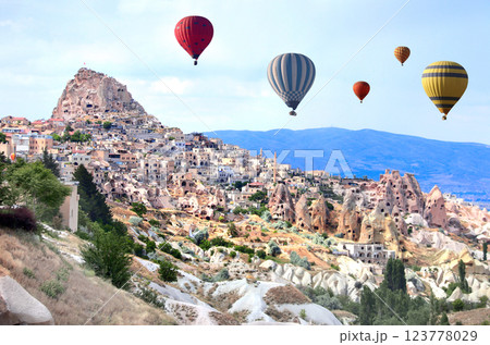 The balloon flight, famous tourist attraction of Cappadocia. Air balloons and carved houses in rock in Pigeon Valley, Uchisar, Cappadocia, Anatolia, Turkey The balloon flight, famous tourist attraction of Cappadocia. Air balloons and carved houses in rock in Pigeon Valley, Uchisar, Cappadocia, Anatolia, Turkey 123778029