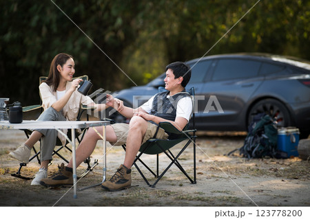 A couple is locking eyes while smiling at each other while pouring drink at table on camping ground. A couple is locking eyes while smiling at each other while pouring drink at table on camping ground. 123778200