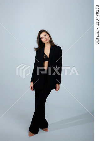 Businesswoman posing barefoot wearing black suit and lace bra in studio Businesswoman posing barefoot wearing black suit and lace bra in studio 123778253