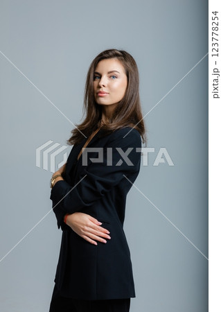 Businesswoman posing barefoot wearing black suit and lace bra in studio 123778254