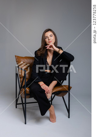 Young businesswoman posing barefoot sitting on a modern chair Young businesswoman posing barefoot sitting on a modern chair 123778258