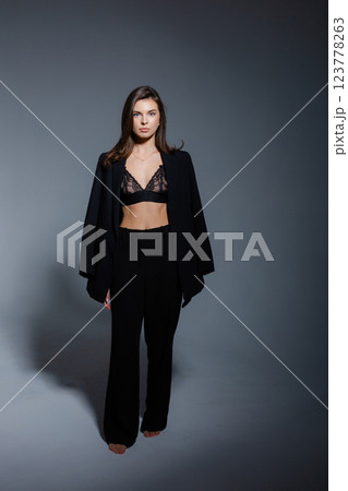 Confident businesswoman posing with jacket and bra on dark background Confident businesswoman posing with jacket and bra on dark background 123778263