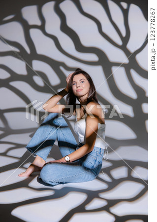 Young woman posing sitting on floor with projected shadows 123778267