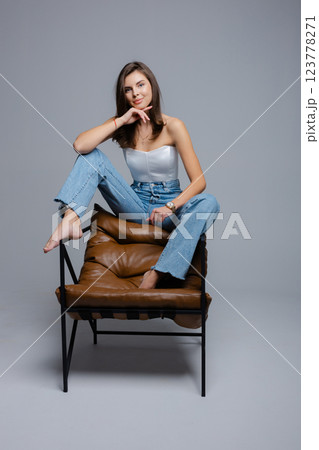 Young woman sitting on modern armchair touching her hair Young woman sitting on modern armchair touching her hair 123778271