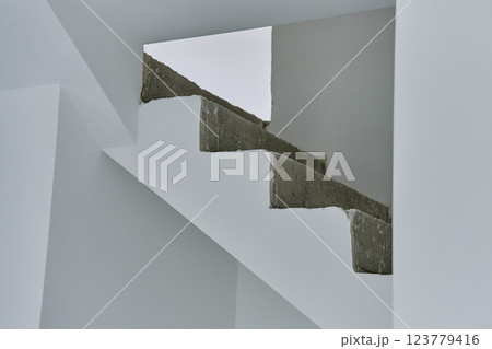 Unfinished concrete staircase in modern minimalist interior. New apartment with raw construction elements and white walls. Building under repair Unfinished concrete staircase in modern minimalist interior. New apartment with raw construction elements and white walls. Building under repair 123779416